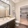 bathroom with a large mirror, connected closet, and modern counter-top