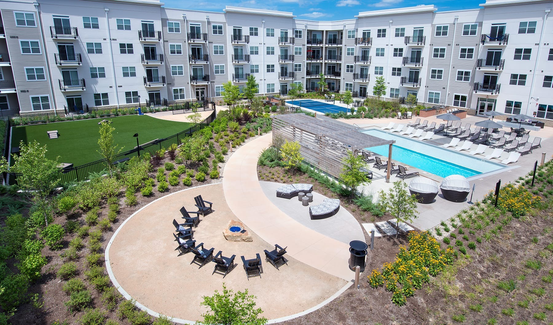 Living Begins Here balcony view of outside courtyard, firepit, and resort-style pool showing ample seating and landscaping